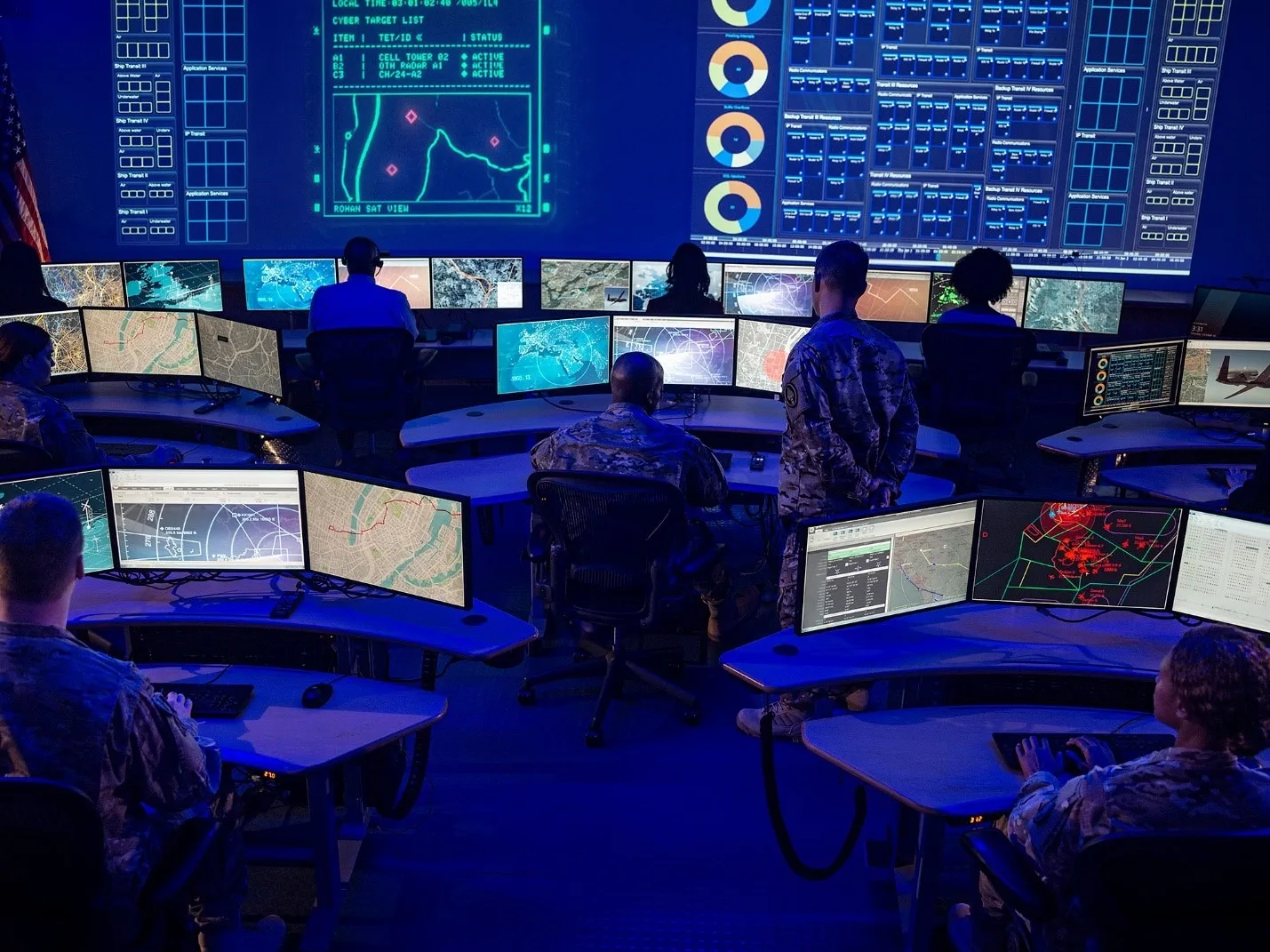 A joint command floor with operators at multi-screen consoles beneath a wall-sized shared operating picture.